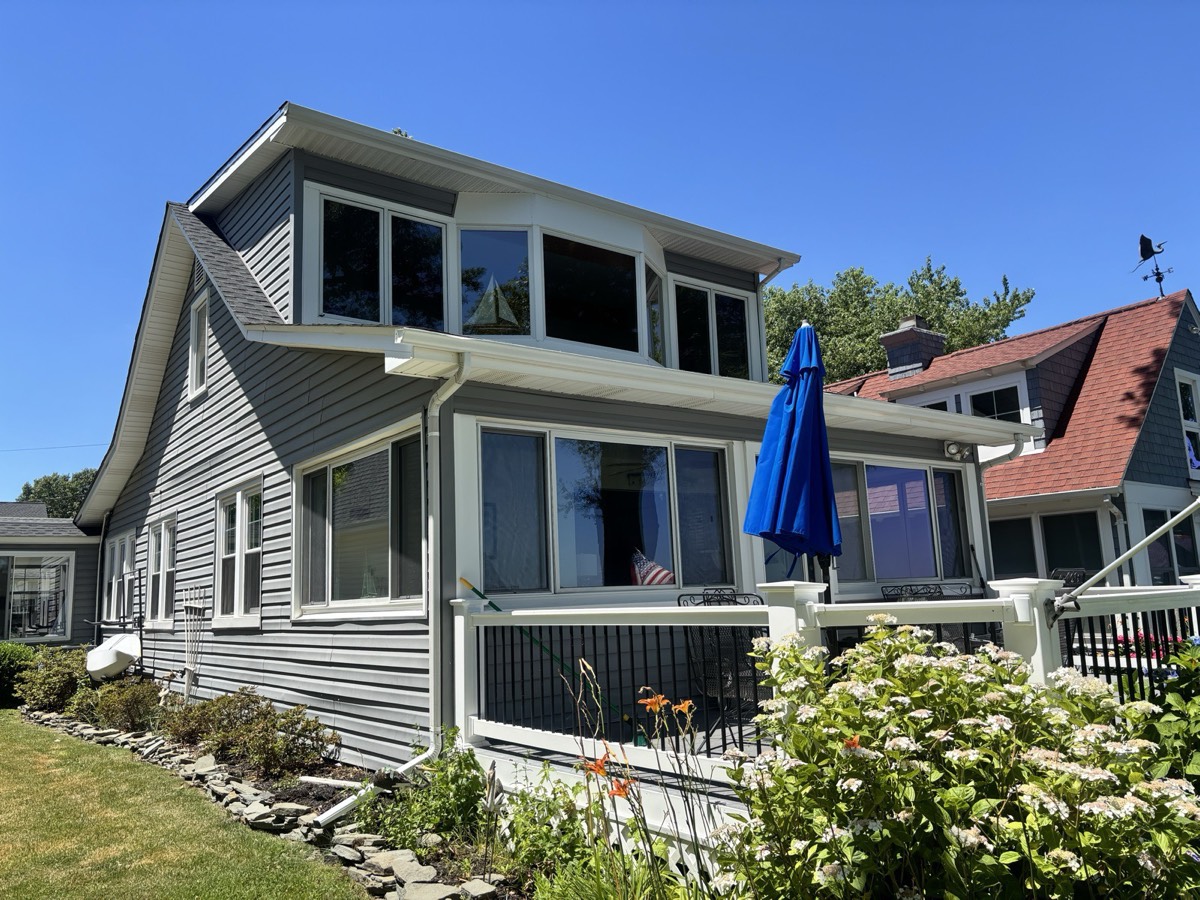 Gray cottage home with sunroom windows cleaned to a streak-free shine